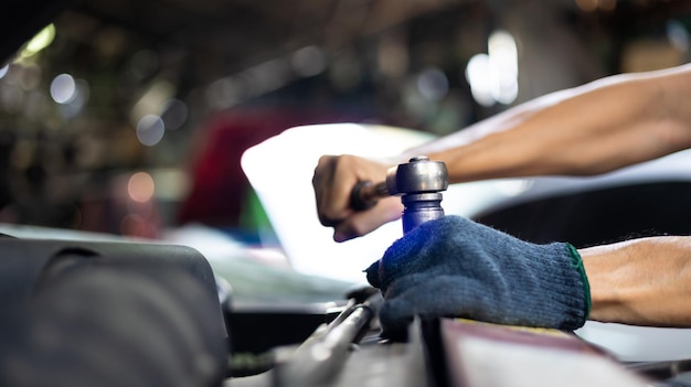 Closeup hand and spanner engineer mechanic male repairs and\
service car in garage car maintenance and auto service garage\
concept