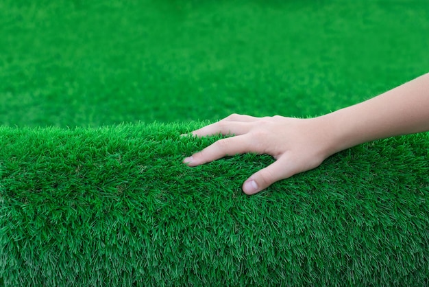 Closeup of hand stroking a roll of soft artificial turf Nice touch of clean and antibacterial grass