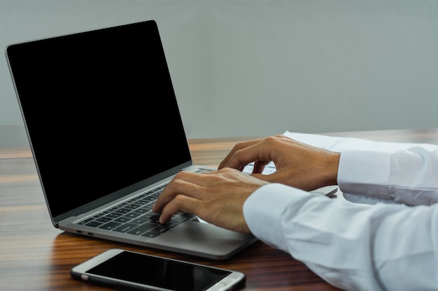 Closeup hand typing keyboard computer working in office, Businessman using computer notebook looking on screen