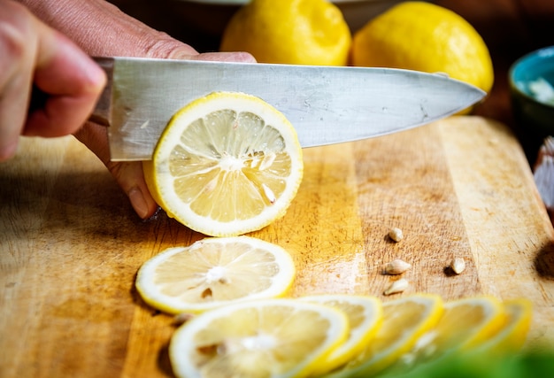 Photo closeup of hand with knife cutting lemon