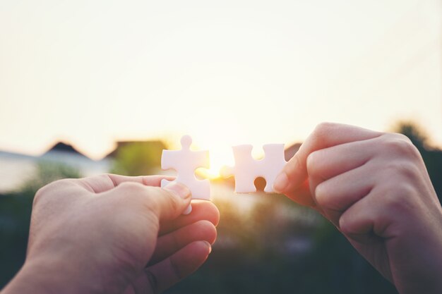 Closeup hand of woman connecting jigsaw puzzle with sunlight, symbol of association