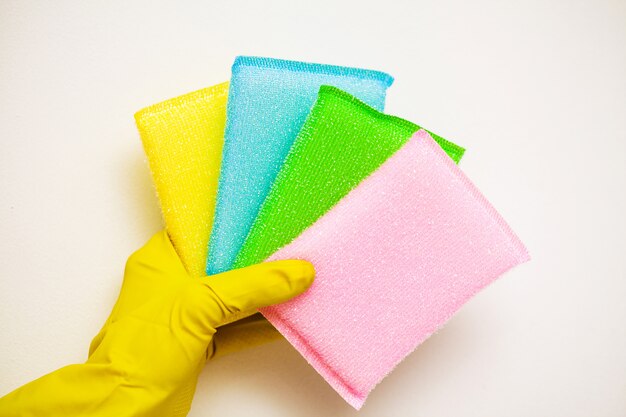 Closeup of hand in yellow gloves holding cleaning supplies