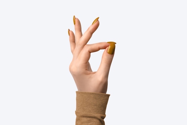 Photo closeup of hand of a young woman with orange manicure on nails against white background