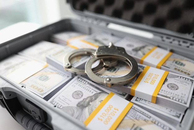 Closeup of handcuffs on pile of cash in suitcase criminal income and illegal cash concept