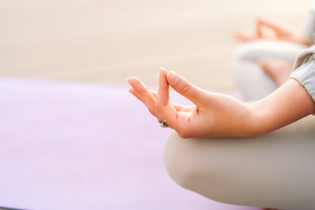 Closeup handen van onherkenbare jonge vrouw mediteren op yoga mat in lotushouding hand in hand