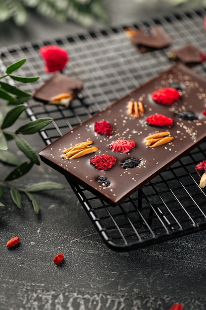 Крупным планом на плитке шоколада ручной работы с орехами пекан и сушеными ягодами