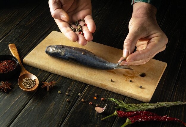 Близкий взгляд на руки, добавляющие сухой перец в рыбу Clupea