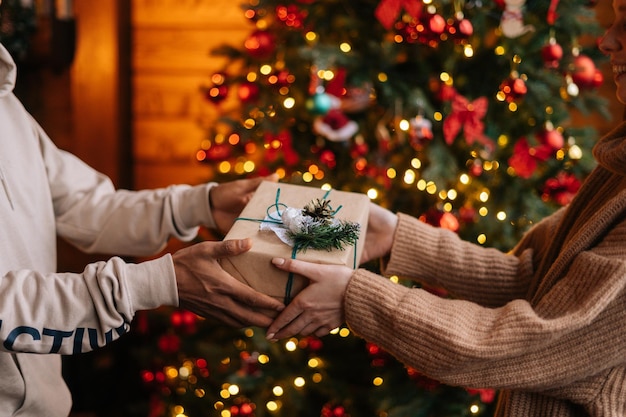 Photo closeup hands of african american man giving christmas gift to caucasian girlfriend