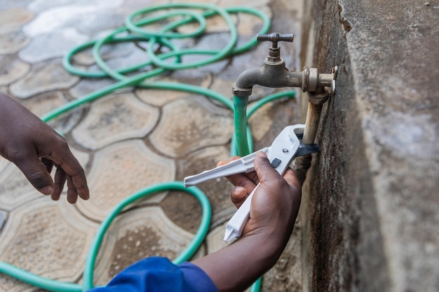 Closeup of the hands of an African plumber fixing the outside tap