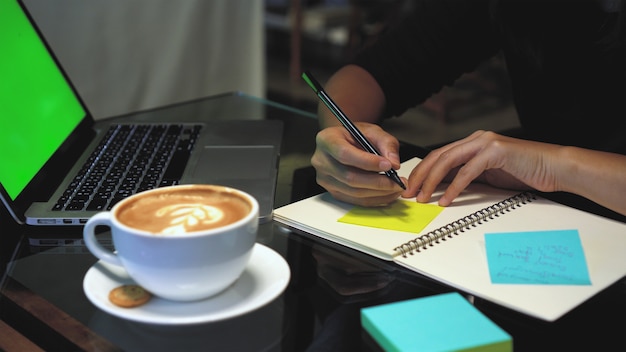 Closeup hands of Asian businesswoman working and writing on paper Notes over the notebook