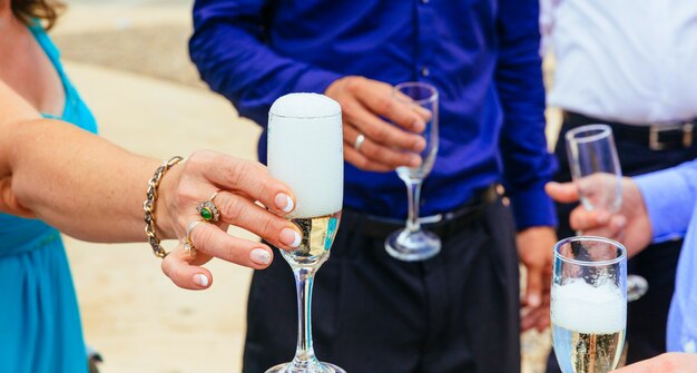 Closeup hands of the bride and groom with glasses  champagne