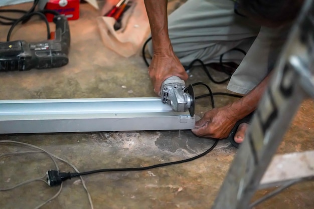 Closeup hands of builder holding electric angle grinder working cutting aluminum lumber