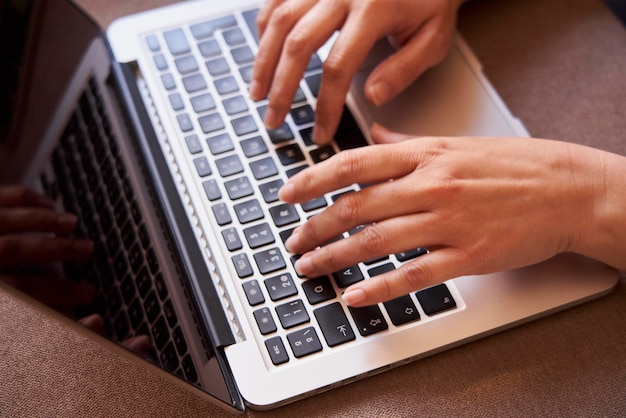 Primo piano delle mani della donna di affari che digita con un computer portatile