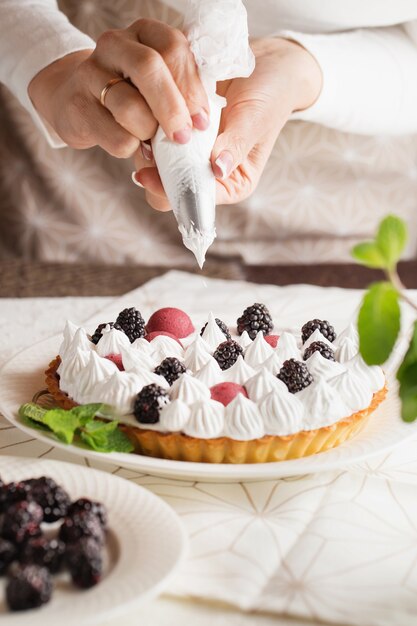 Mani del primo piano dello chef con crema sacchetto di pasticceria