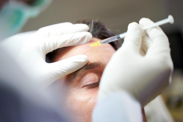 Closeup hands of doctor in medical grove holding beauty skin syringe injecting the customer