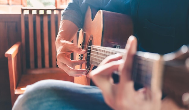 Closeup of the hands and fingers of a male musician playing an acoustic guitarMusical guitar