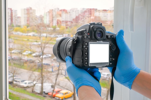 Closeup of hands holding a camera to take a photo from a house window Quarantine health concept