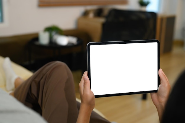 closeup of hands holding digital tablet with a blank display lying on sofa