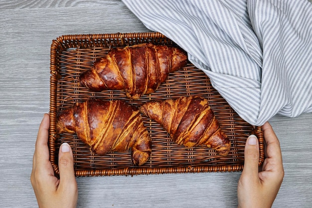 closeup hands holding a esparto halfah basket with Fresh croissants