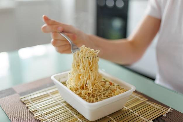 A closeup of hands holding a fork digging into a plate of fast food in a kitchen