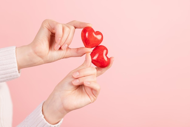 Primo piano mani che tengono il cuore su sfondo rosa concetto di san valentino