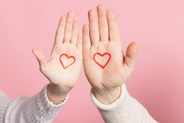 Primo piano mani che tengono il cuore su sfondo rosa concetto di san valentino