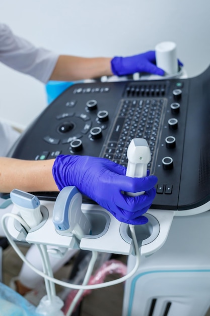 A closeup of the hands holding the ultrasonic probe of an ultrasound machine on which a special gel is applied selective focus