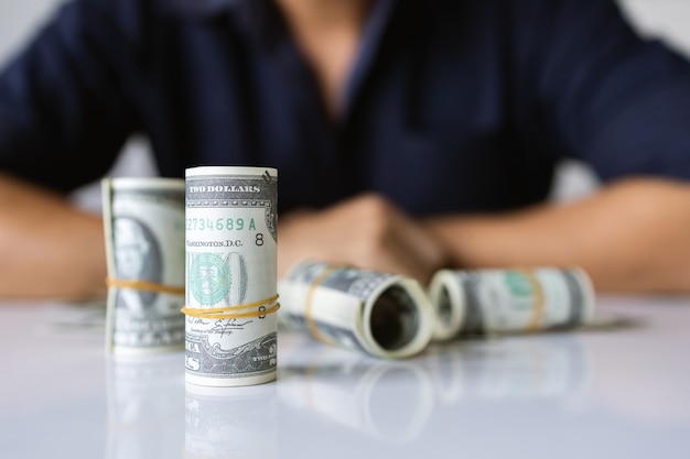 Closeup hands holding us dollar bills with soft-focus and over light in the background