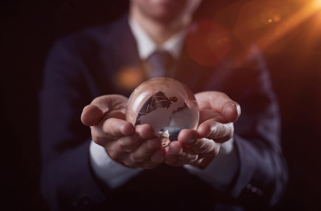 Photo closeup of hands holding world sphere in brown