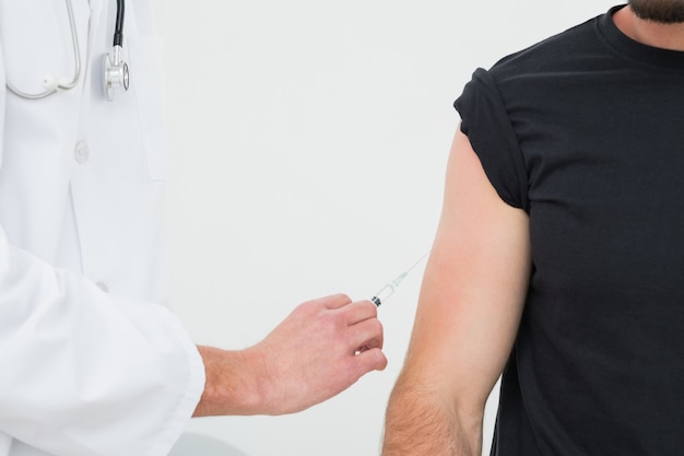 Closeup of hands injecting a young male patients arm