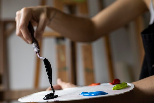 Closeup of the hands of Latin American artist showing the palette and palette knife with the paints