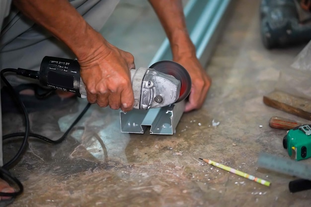 建設現場で金属を握る電気角度磨き機の作業を見たマスターのクローザップの手