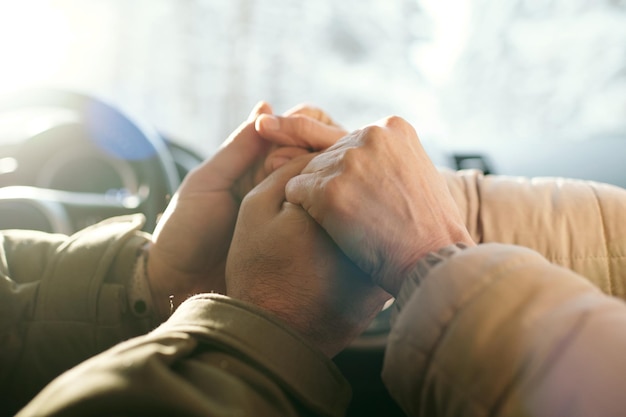 Closeup of hands of mature couple sitting in car during their trip