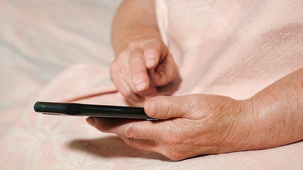 Closeup of the hands of an old woman with a phone.