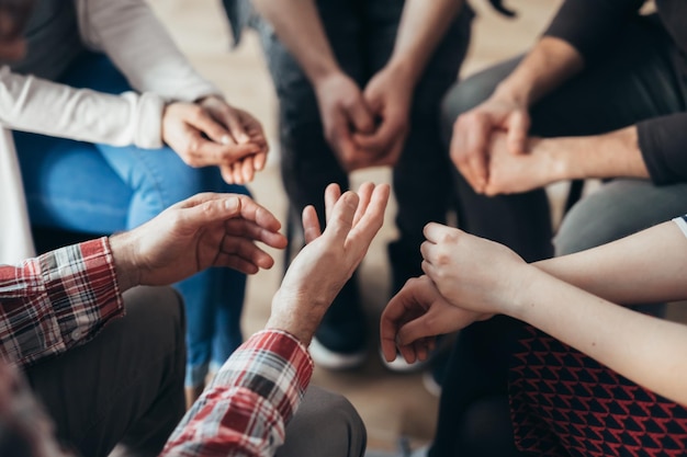 Closeup of hands of people sitting in a circle during a therapy group meeting