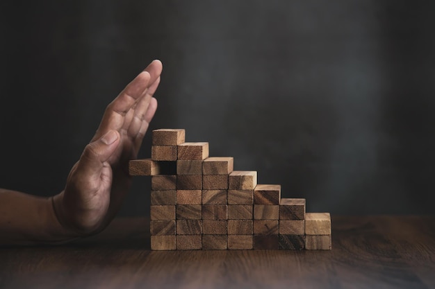 Closeup hands prevent wooden block not falling