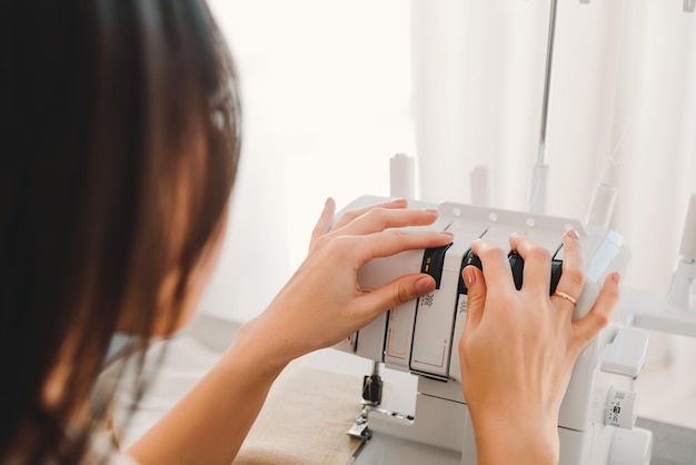 A closeup of the hands of a seamstress setting up a seam on a sewing machine