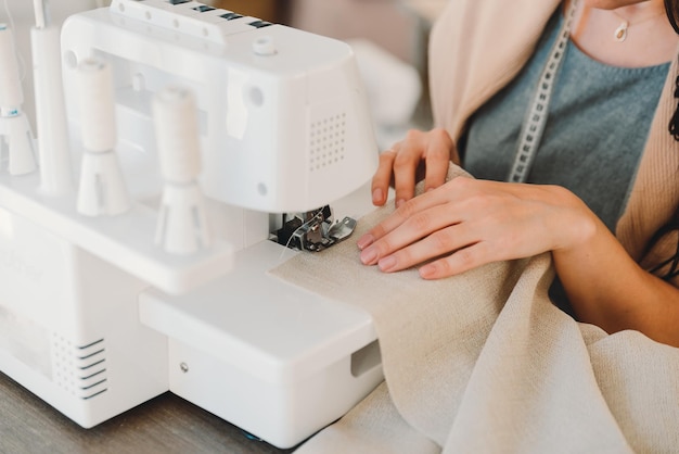 Closeup of the hands of a seamstress who sews curtains on a sewing machine