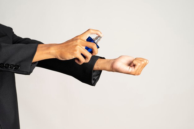 Photo closeup of hands spraying perfume on hands on blue background