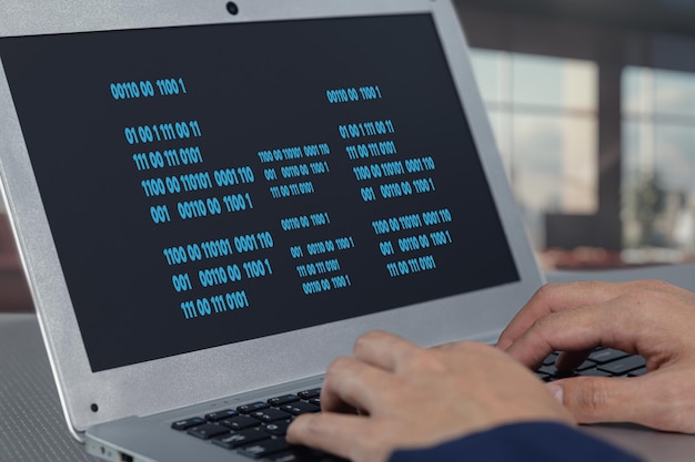 CloseUp of Hands Typing Code on Laptop with Binary Display