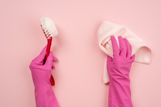 Closeup hands wearing in latex gloves holding a rag and household brush. Top view