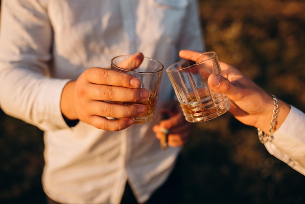 Closeup of hands with clinking whiskey glasses Cheers mate