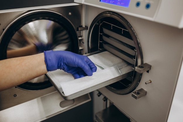 Closeup hands with gloves in the places medical autoclave for sterilising surgical