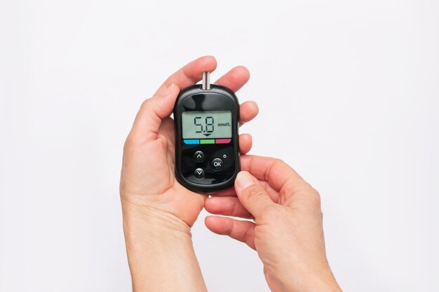 Closeup of the hands of a woman using a glucose meter to measure blood sugar level Health care