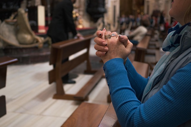 Primo piano delle mani di una donna mentre pregava in chiesa