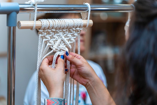 Closeup of the hands of a young girl making macrame in a workshop