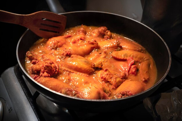 Closeup hands of young latin woman cooking chicken and spices in barbecue sauce at home