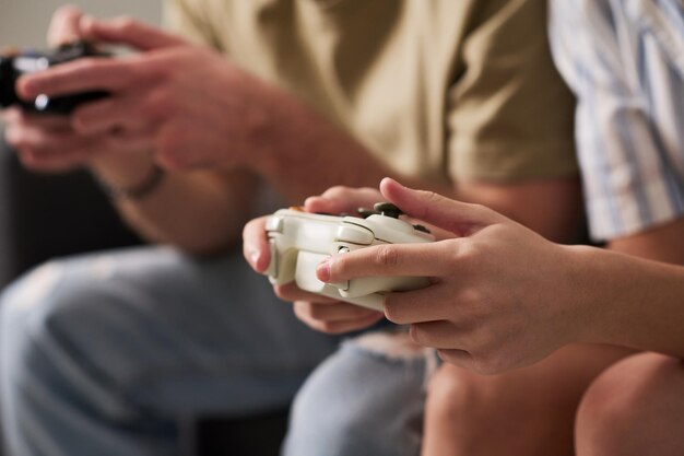 Closeup of hands of young man and woman pressing buttons on gamepads