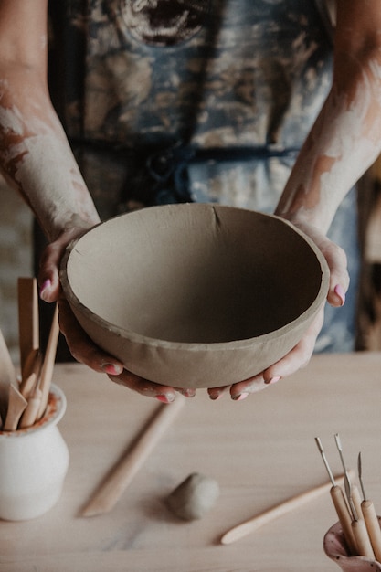 Closeup on hands of young master with large clay plate