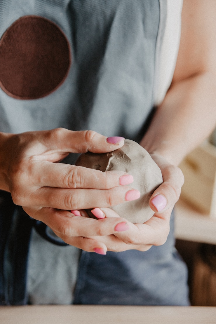Photo closeup on hands of young master with large piece of clay